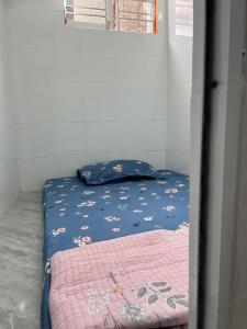 a bed with a blue blanket with flowers on it at Homestay Hoa Anh in Hai Phong
