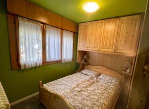 a bed in a room with green walls and wooden cabinets at Il Nido Dell'Aquila-Piancavallo in Piancavallo