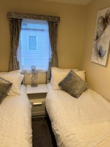 Duas camas num pequeno quarto com uma janela em Beautiful Spacious Holiday Home - Romney Sands em New Romney