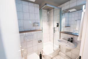 a white bathroom with a shower and a sink at City Park Hotel in Frankfurt Oder +27 photos