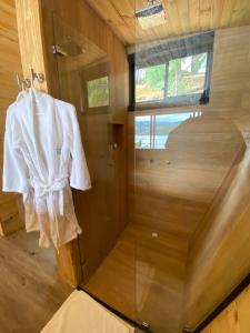 una bata blanca colgando en una ducha en una habitación en GLAMPING BY NAQUA, en Pantano Redondo