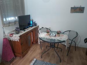 a room with a table and a tv and a table and chairs at ZEHAVI Guest House in Lahavot HaBashan
