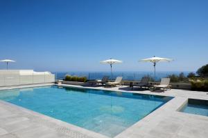 a swimming pool with chairs and umbrellas on a building at Mayu Suites in Pyrgos