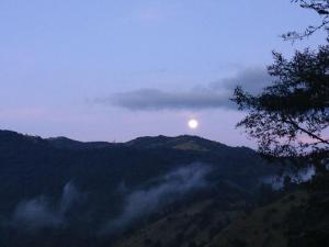 una vista del sol saliendo sobre una montaña en Finca Petrona, en Mindo