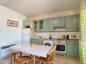 une cuisine avec des armoires vertes, une table et des chaises dans l'établissement Appartement Mauguio-Carnon, 2 pièces, 6 personnes - FR-1-715-54, à Mauguio