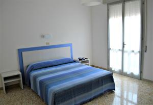 Un dormitorio con una cama azul y una ventana en Hotel Canoa, en Cervia