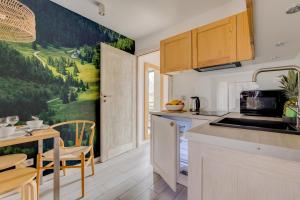 a kitchen and dining room with a painting on the wall at Giewont View Apartamenty z widokiem - Butikowe & Sauna - Grunwaldzka Krupówki Centrum Zakopane by RentiloPL in Zakopane