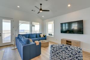 Una sala de estar con un sofá azul y un televisor. en Modern Galveston Vacation Rental Steps to Beach!, en Galveston