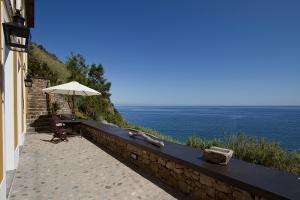 a stone wall with an umbrella next to the ocean at Casa do Lado in Povoação