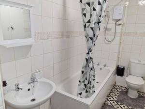 a bathroom with a sink and a toilet and a shower curtain at The Lawrence apartment in Bristol