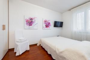 ein weißes Schlafzimmer mit einem Bett und einem TV in der Unterkunft GIOTTO Guesthouse in Due Carrare