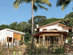 a house with palm trees in front of it at Casa do Jardim in Serra Grande