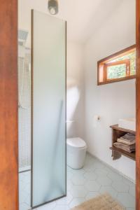 a bathroom with a toilet and a glass shower door at Casa do Jardim in Serra Grande