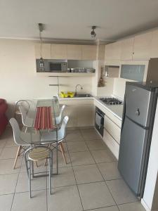 La cuisine est équipée d'une table, de chaises et d'un réfrigérateur. dans l'établissement Condominio Laguna Vista Algarrobo, à Algarrobo