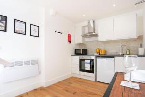 バッキンガムにあるCentral Buckingham Apartment #4 with Free Parking, Pool Table, Fast Wifi and Smart TV with Netflix by Yoko Propertyの白いキャビネットとワイングラス付きのテーブルが備わるキッチン