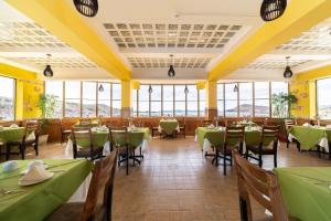 a restaurant with green tables and chairs and windows at Hotel Qalasaya in Puno