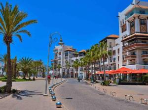 una calle con palmeras y edificios en una playa en Marina Agadir - Luxury Pool view apartment 2Bdr, en Agadir