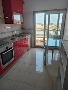 a kitchen with red cabinets and a table with a view at MARINA SOL VIVEIRO in Viveiro