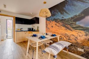 a kitchen with a table and chairs with a painting on the wall at Giewont View Apartamenty Butikowe & Sauna Grunwaldzka by RentiloPL in Zakopane