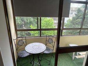 une table et deux chaises devant une fenêtre dans l'établissement Olympic Apartment, à Braga