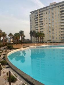 une grande piscine bleue en face d'un grand bâtiment dans l'établissement Condominio Laguna Vista Algarrobo, à Algarrobo