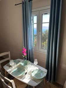 Assos BLUE house في أسوس: طاولة مع أطباق وأكواب نبيذ ونافذة