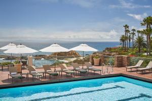 uma piscina com cadeiras e guarda-sóis e o oceano em Montage Laguna Beach em Laguna Beach