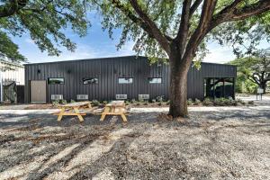 two picnic tables under a tree in front of a building at Wanderstay Boutique Hotel in Houston