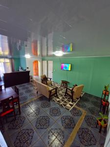 a living room with chairs and a tv on a wall at Micheck beach house in Tortuguero