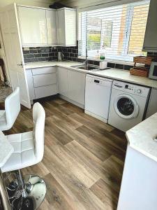 uma cozinha com armários brancos e uma máquina de lavar e secar roupa em Rycroft em North Runcton