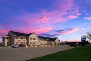 a building in a parking lot with a cloudy sky at Best Western Vermillion Inn in Vermillion