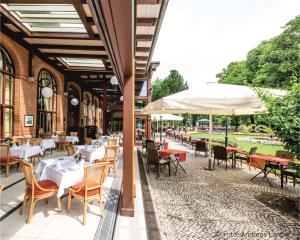 een restaurant met tafels en stoelen en een parasol bij Dorint Herrenkrug Parkhotel Magdeburg in Maagdenburg