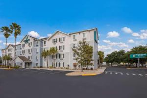 a large white building with palm trees in a parking lot at WoodSpring Suites Orlando North - Maitland in Orlando