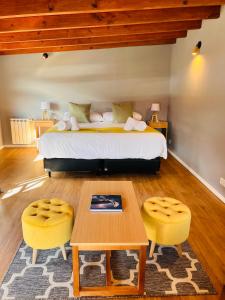 a bedroom with a bed and a table and yellow chairs at Desierto Suites in El Chalten