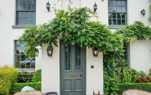 una puerta delantera de una casa blanca con una puerta verde en The Vicarage, en Holmes Chapel