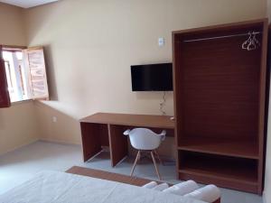 a bedroom with a desk with a computer and a chair at Hotel do Carmo in Piracuruca