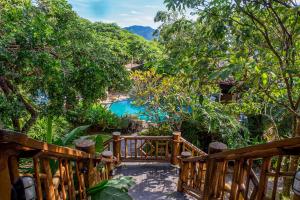 een houten brug die leidt naar een zwembad in een tuin bij Hotel Alemão Beach de Ilhabela in Ilhabela