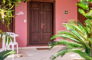 una casa rosa con una puerta de madera y algunas plantas en Hotel Alemão Beach de Ilhabela en Ilhabela