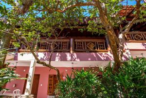 ein rosafarbenes Gebäude mit einem Baum davor in der Unterkunft Hotel Alemão Beach de Ilhabela in Ilhabela