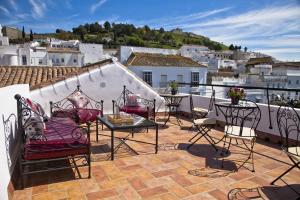 Un patio con sillas y una mesa en el balcón. en Apartamentos La Casa de la Alameda, en Medina Sidonia