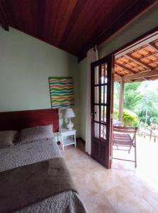 卢米亚PARAÍSO ROMÂNTICO - para casais - cozinha para preparar suas refeições的一间卧室，里面有一张床和一扇推拉玻璃门