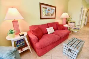 格爾夫海岸的住宿－Caribbean 503，客厅里红色的沙发,配有两盏灯
