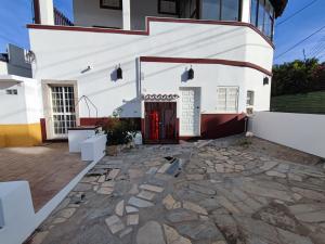 une maison blanche avec une porte rouge et une cour en pierre dans l'établissement Algarve, renovated T1 apartment in S Bras de Alportel, à São Brás de Alportel