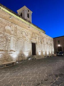 a large stone building with two benches in front of it at Appartamenti Sole e Luna in Tropea