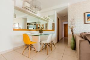 a dining room and kitchen with a glass table and yellow chairs at Apt incrível para sua família! Com churrasqueira in Cuiabá