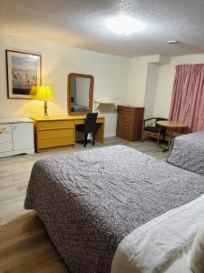 Habitación de hotel con cama, escritorio y espejo. en Uptown Motel, en Estevan