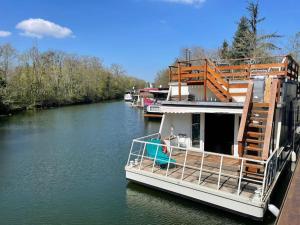 ein Boot an einem Fluss angedockt ist in der Unterkunft PARIS - Maison flottante - Boat House en pleine nature aux portes de Paris et du Stade de France in Vigneux-sur-Seine