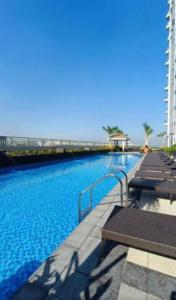 a large swimming pool with benches and blue water at Coast Residences Penthouse with skyline and manila bay view in Manila