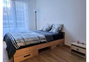 a bedroom with a bed with a blue comforter and a window at Superbe appartement avec jardin proche Versailles in Saint-Cyr-lʼÉcole