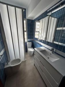 Baño de azulejos azules con aseo y lavamanos en Sea-side Villa in la Zenia, en Alicante